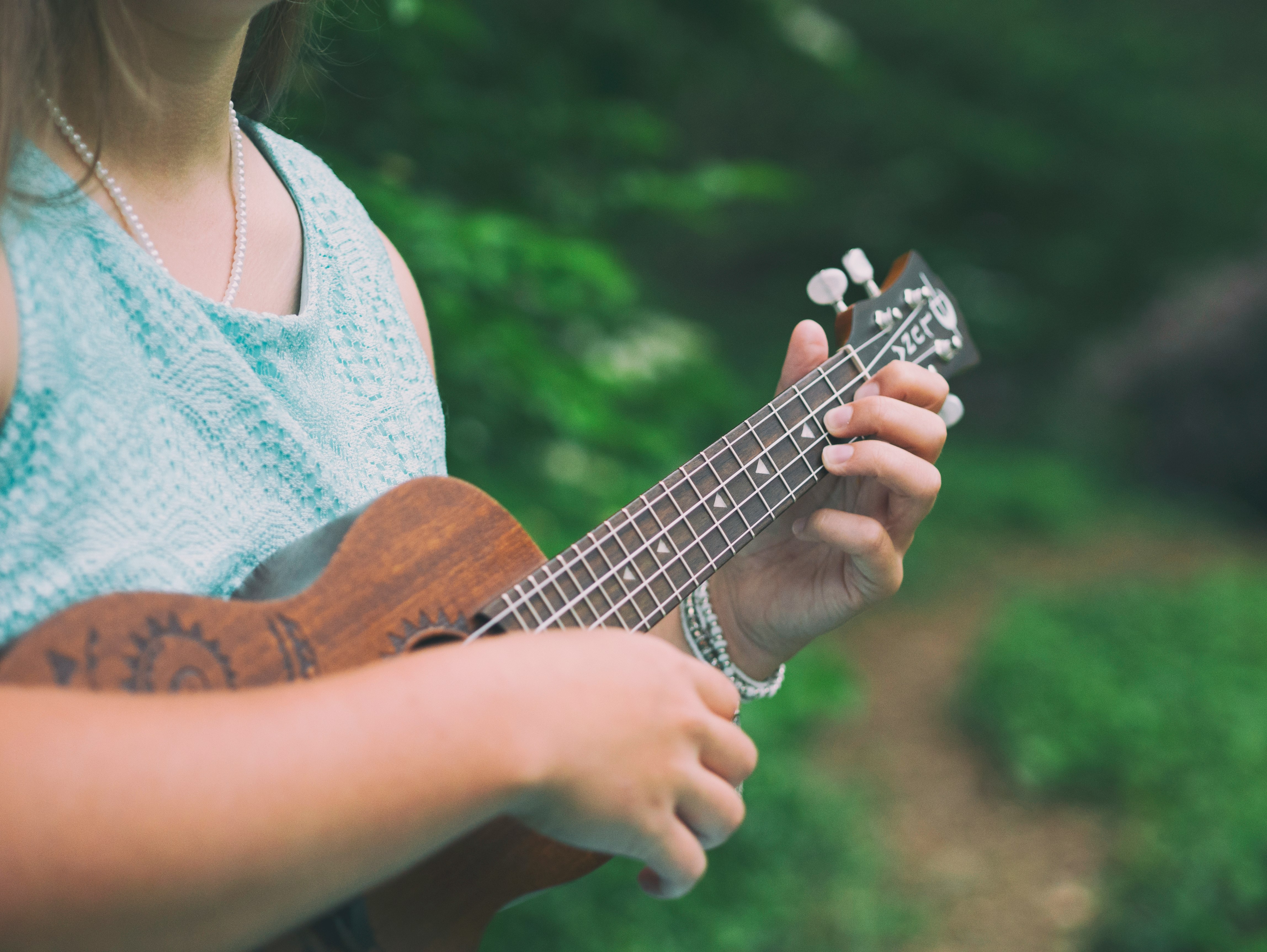 woman wearing blue sleeveless top holding brown ukulele